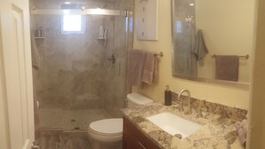 Une salle de bain équipée d’une douche, de toilettes, d’un lavabo et d’un grand miroir.