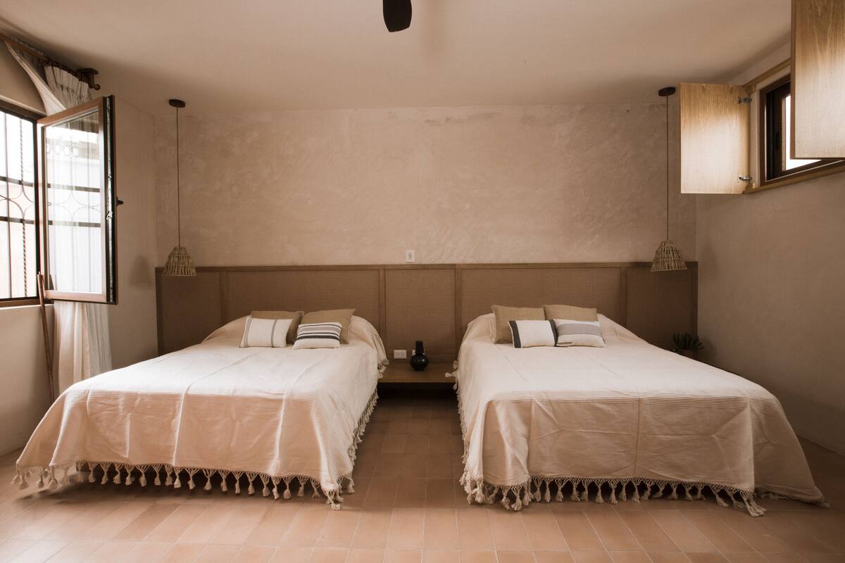 Ein Zimmer mit zwei Betten, einem Fenster und einer Tür.