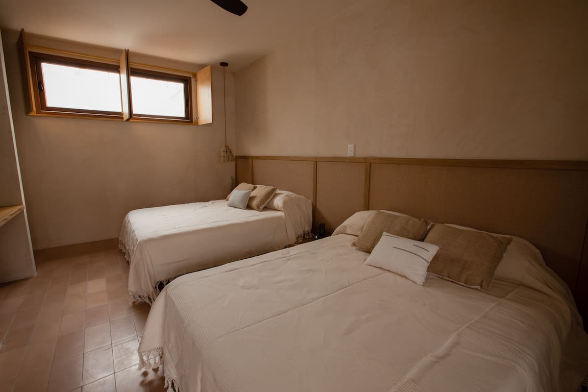 Ein Zimmer mit zwei Betten, einem Fenster und einem Deckenventilator.