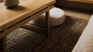 A cozy room with a wooden table, a woven basket, a round woven wall hanging, and a hanging light fixture. - Casa Montore by Barrio Mexico (Guadalajara)