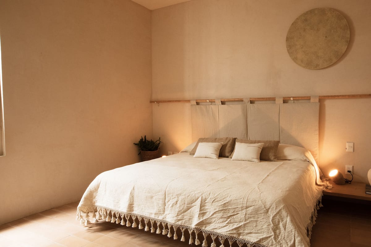 Ein Schlafzimmer mit einem großen Bett, einem Nachttisch mit Lampe und einer runden Wanddekoration.