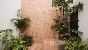 A small, enclosed outdoor area with a tiled floor, surrounded by potted plants and a brick wall. - Casa Montore by Barrio Mexico (Guadalajara)
