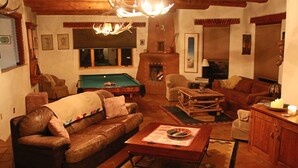 Una sala de estar acogedora con mesa de billar, sofá de cuero y chimenea.