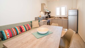 A compact kitchen with a dining area, a built-in oven, and a refrigerator. - T' adelfia  -  ERMIS (Corfu)