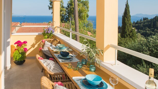 A terrace with a wooden table set for dining, overlooking a coastal landscape. - T' adelfia  -  ERMIS (Corfu)