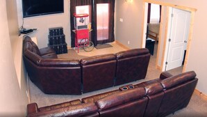 Un salon avec un canapé d’angle, un distributeur automatique rouge et un fauteuil roulant dans un coin.