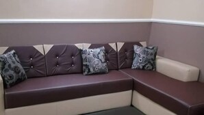 Uma sala de estar moderna com um sofá seccional, uma mesa de centro preta e almofadas decorativas estampadas.
