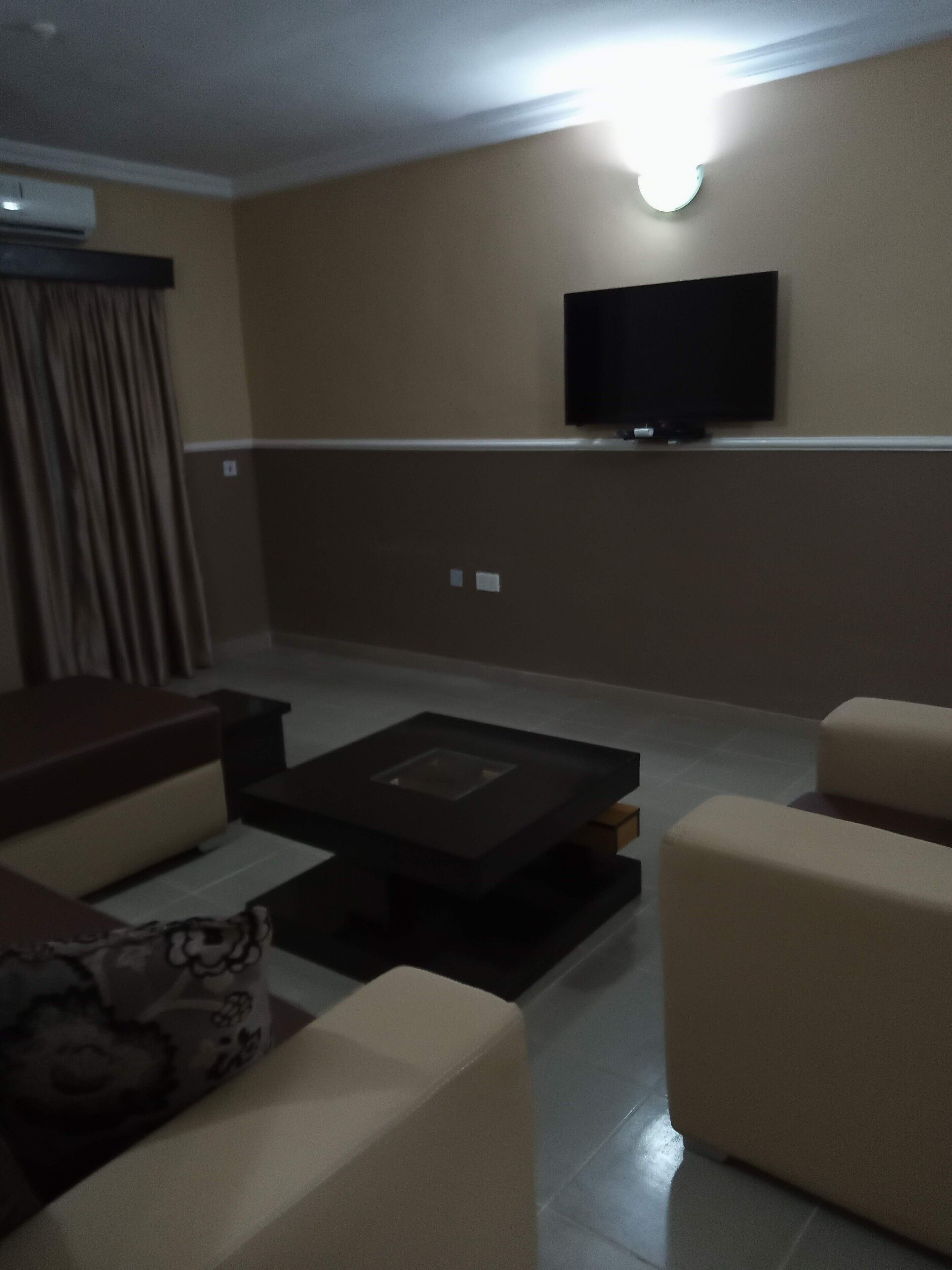 Un salon avec un téléviseur à écran plat fixé au mur, un canapé et une table basse.