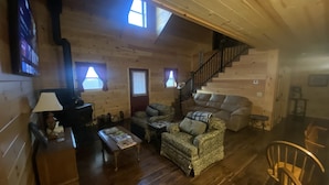 L’intérieur chaleureux d’un chalet avec des murs en bois, un canapé, une table basse et un escalier.