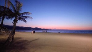 Una playa con palmeras y un atardecer.