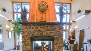 A stone fireplace with a fire, surrounded by a tiled floor with a RiverStone Resort logo.