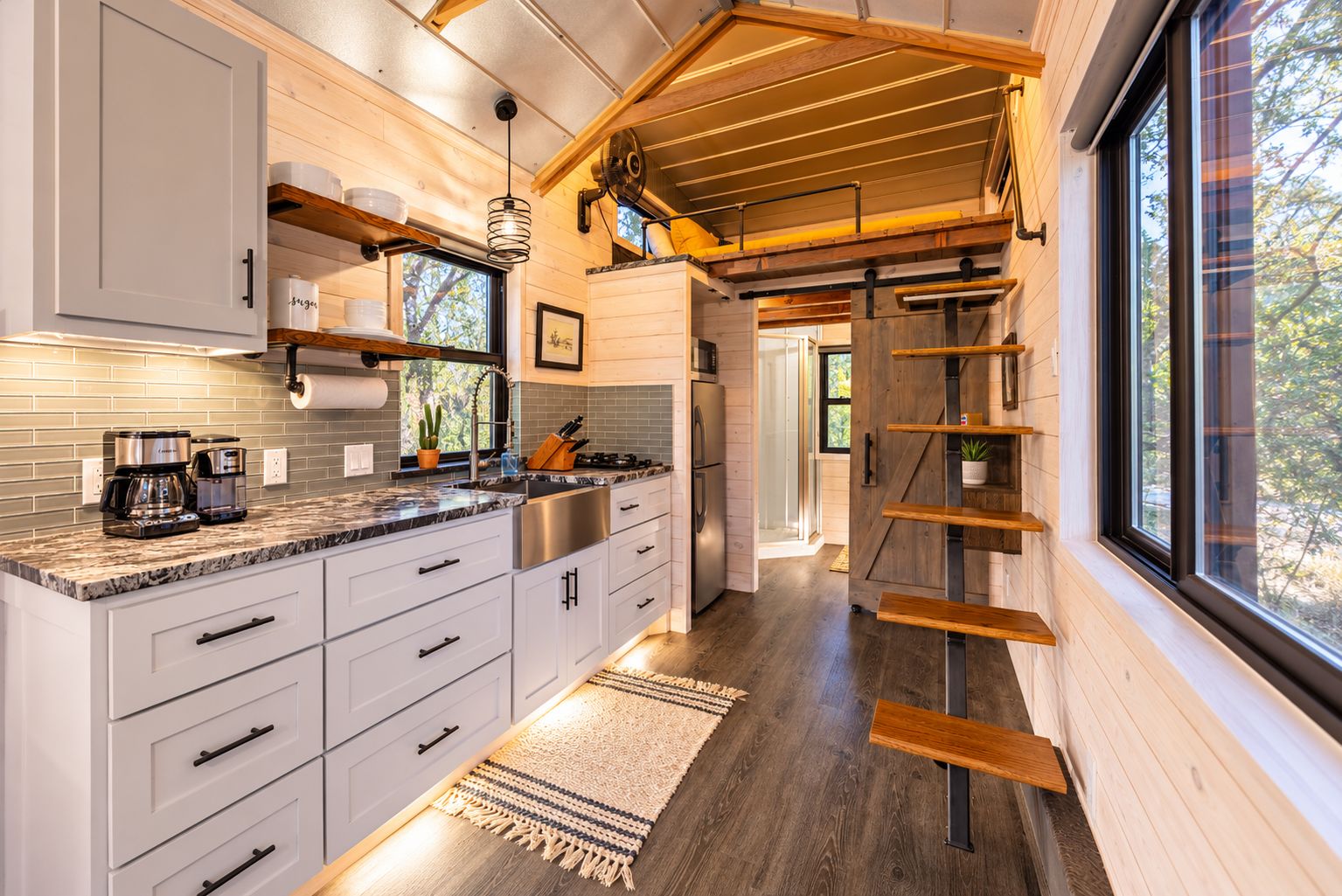 A modern kitchen with white cabinets, a marble countertop, and a wooden ceiling.