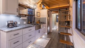 Una cocina moderna con techo de madera, armarios empotrados y encimera con cafetera.