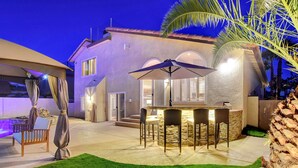 An outdoor patio area with a bar, seating, and a well-lit entrance.