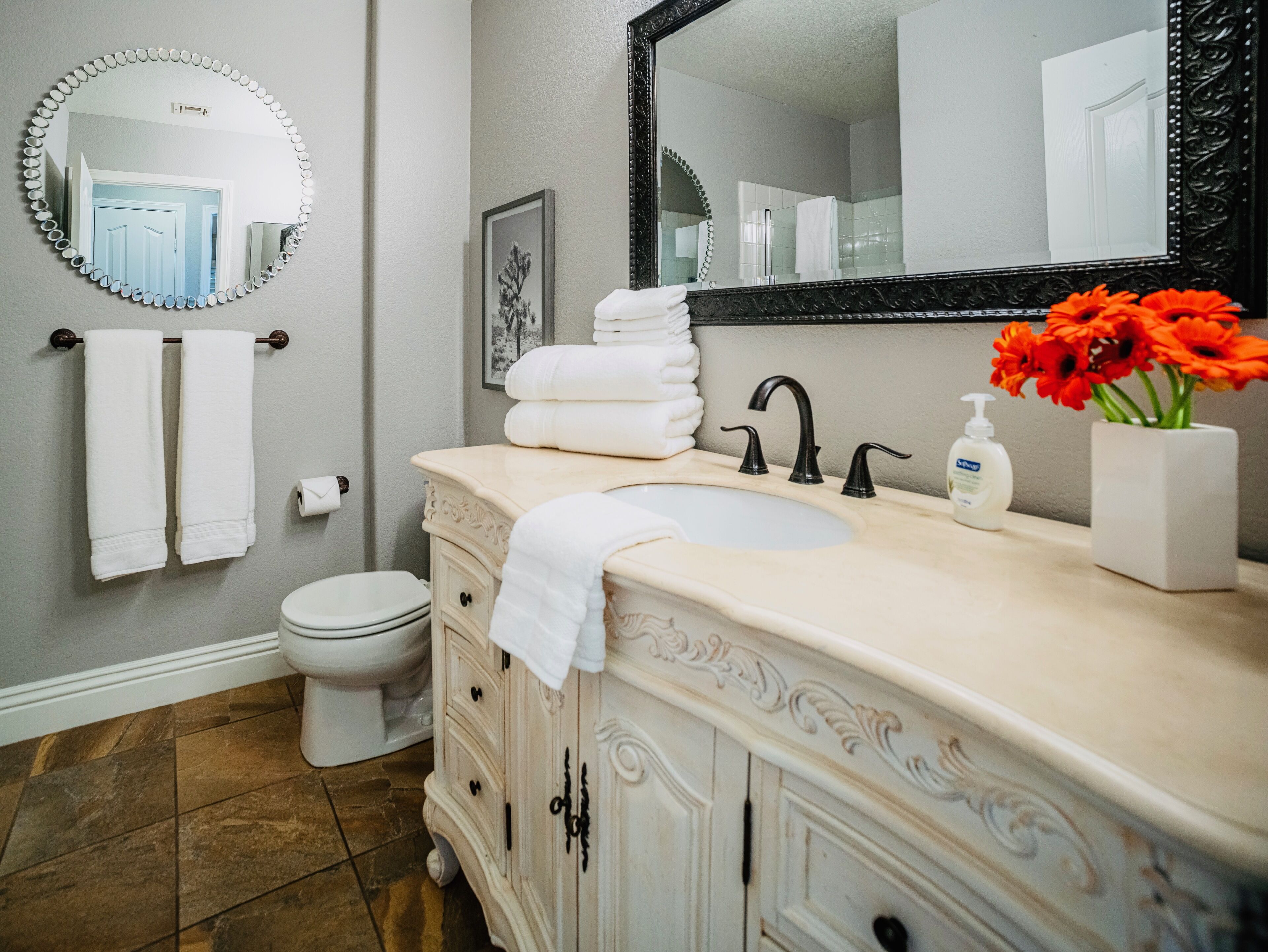 A bathroom with a white vanity, a sink, a mirror, and a toilet.