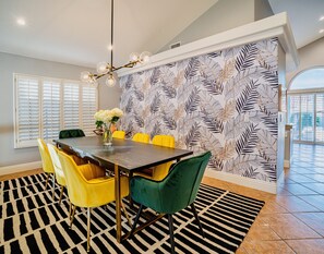 A dining area with a table, chairs, and a patterned wallpaper.