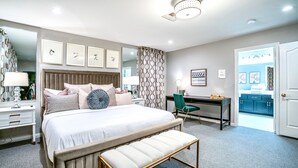 A modern bedroom with a large bed, bedside tables, a desk, and a bench.