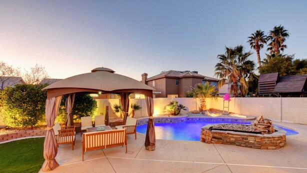 A backyard with a swimming pool, a gazebo, and outdoor furniture.