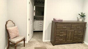 A room with a wooden chair, a cabinet, and a doorway leading to a bathroom. - Spacious Modern Retreat House (Garland)