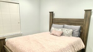 A bedroom with a wooden bed frame, a pink bedspread, and two pillows. - Spacious Modern Retreat House (Garland)