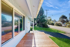 Enjoy a porch with a deck, adjacent to a house with sliding glass doors leading to the backyard.
