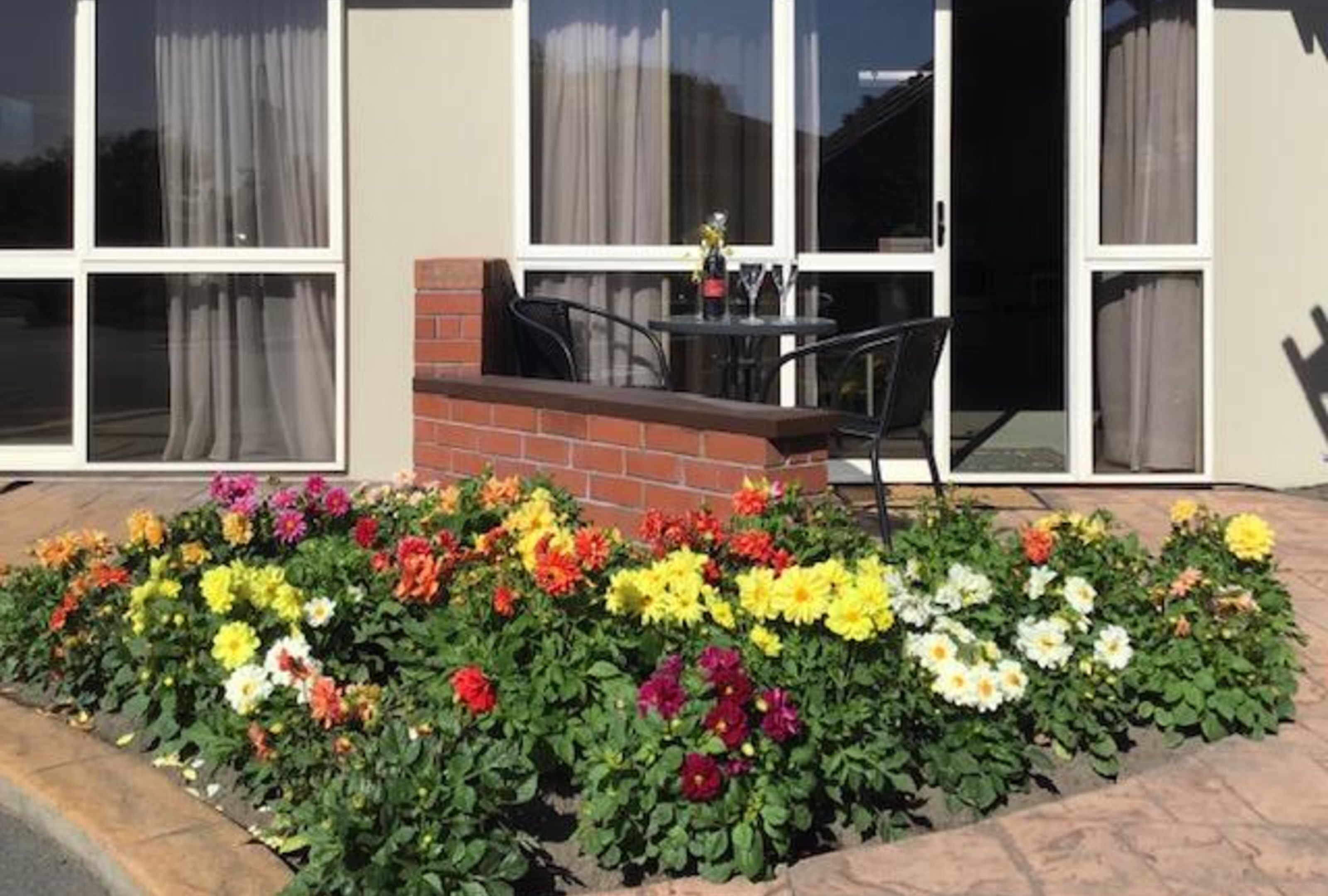 Ein Gebäude mit großen Fenstern, einem Ziegel-Eingang und einem Blumenbeet mit bunten Blumen.