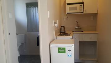 A compact kitchen with a microwave, kettle, and a refrigerator.