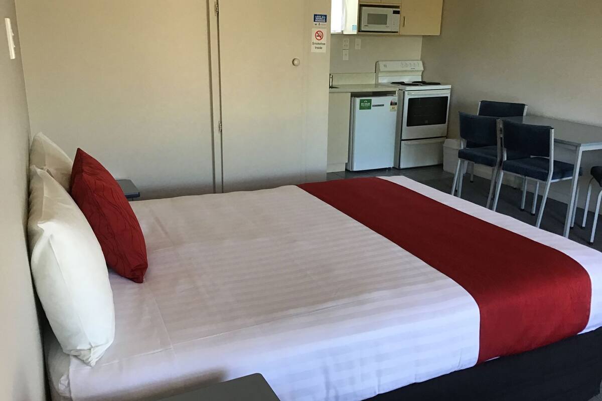 Ein Hotelzimmer mit einem Bett, einer Mikrowelle, einem Kühlschrank und einem Essbereich mit Stühlen.
