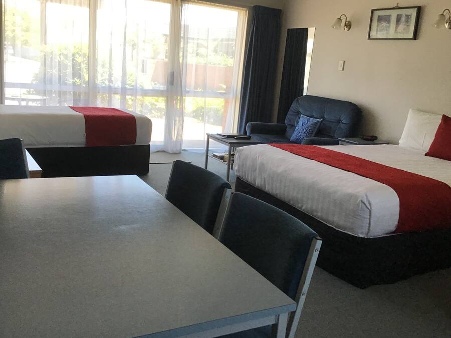 A hotel room with two beds, a dining table, and a chair.