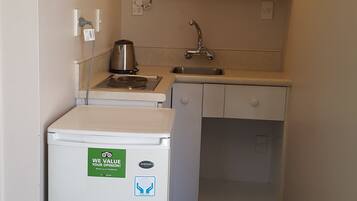 A compact kitchenette with a built-in stove, sink, and a small refrigerator.