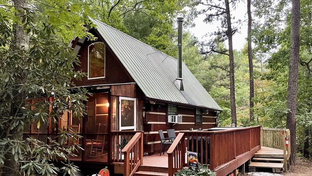 Eine rustikale Holzhütte mit Holzwänden, einem Metalldach und einer Holzterrasse.