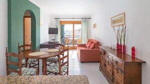 Ein Essbereich mit Holztisch und Stühlen, einer Couch und einem Schrank mit dekorativen Vasen.