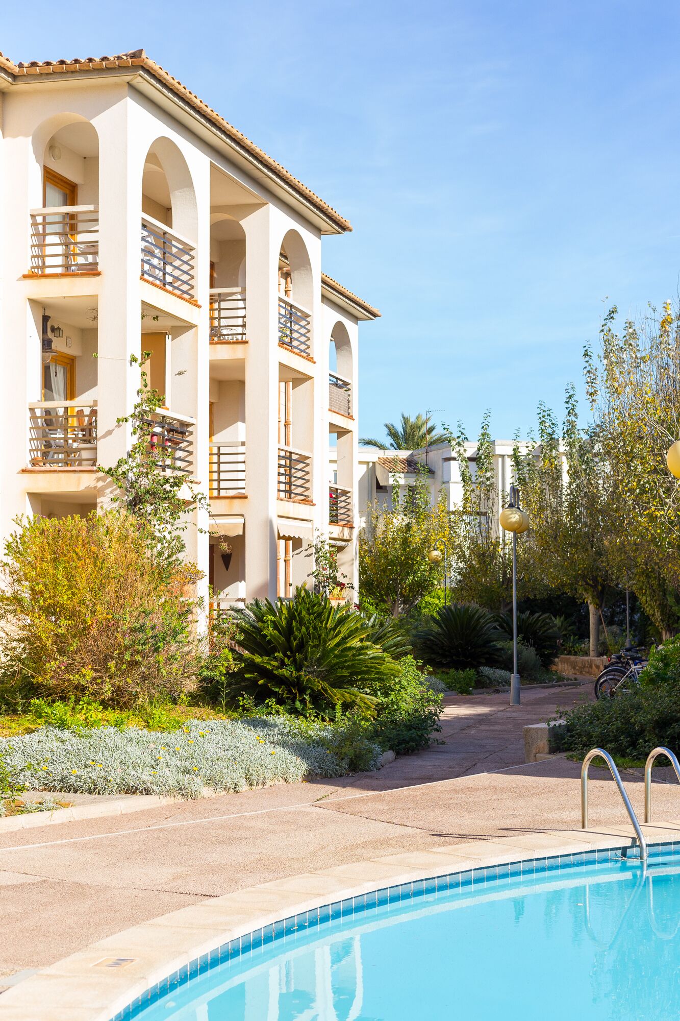 A multi-story hotel with balconies, a swimming pool, and surrounding greenery.