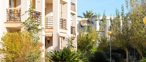 A multi-story hotel with balconies, a swimming pool, and surrounding greenery.