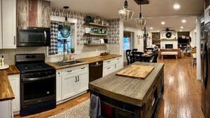 Een moderne keuken met witte kasten, een houten aanrechtblad en een centraal eiland.