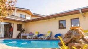 A two-story building with a swimming pool, outdoor seating, and a rock formation. - Bhimi Getaway Guest House (Burnside Bulawayo)