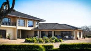 A two-story house with a covered porch and a landscaped front yard. - Bhimi Getaway Guest House (Burnside Bulawayo)