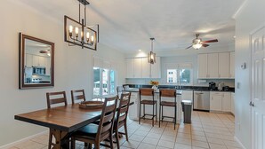 Een moderne keuken met witte kasten, een eettafel met stoelen en een plafondventilator.