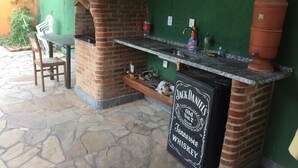 An outdoor bar area with a brick oven and a chalkboard sign advertising Jack Daniel's whiskey. - Chácara Paraíso (Miguel Pereira)