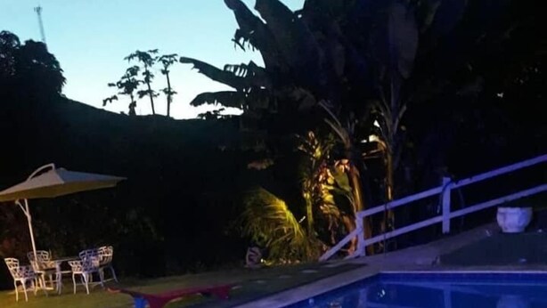 A swimming pool with a metal ladder on one side, surrounded by a tiled deck. - Chácara Paraíso (Miguel Pereira)