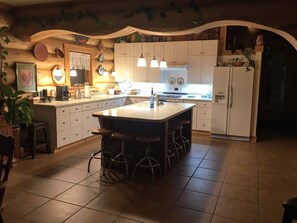 A kitchen with a central island, white cabinets, and hanging pendant lights.