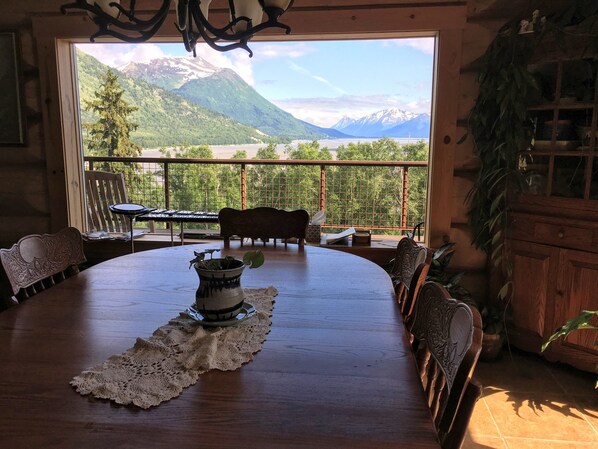 A dining area with a view of mountains and a balcony with a table and chairs.