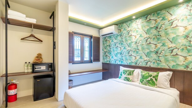 Une chambre d’hôtel équipée d’un lit, d’un petit bureau avec un micro-ondes, d’un extincteur et d’une fenêtre avec des volets.