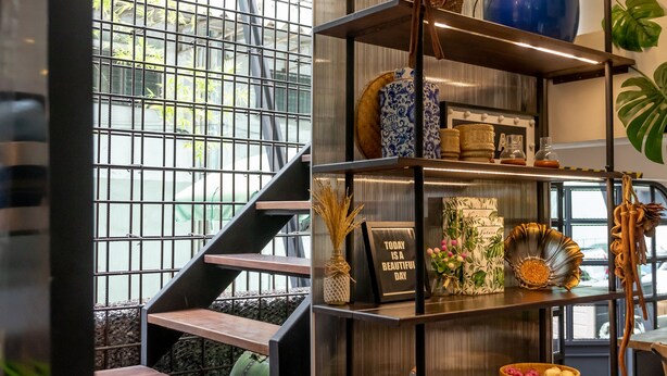 Ein modernes Interieur mit Treppe, einer Metallgitterwand und einem Regal mit Dekorationselementen.