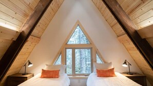 A bedroom with two beds, a window, and wooden beams. - Salted Roots Red Door A-Frame Cabin (Seward)