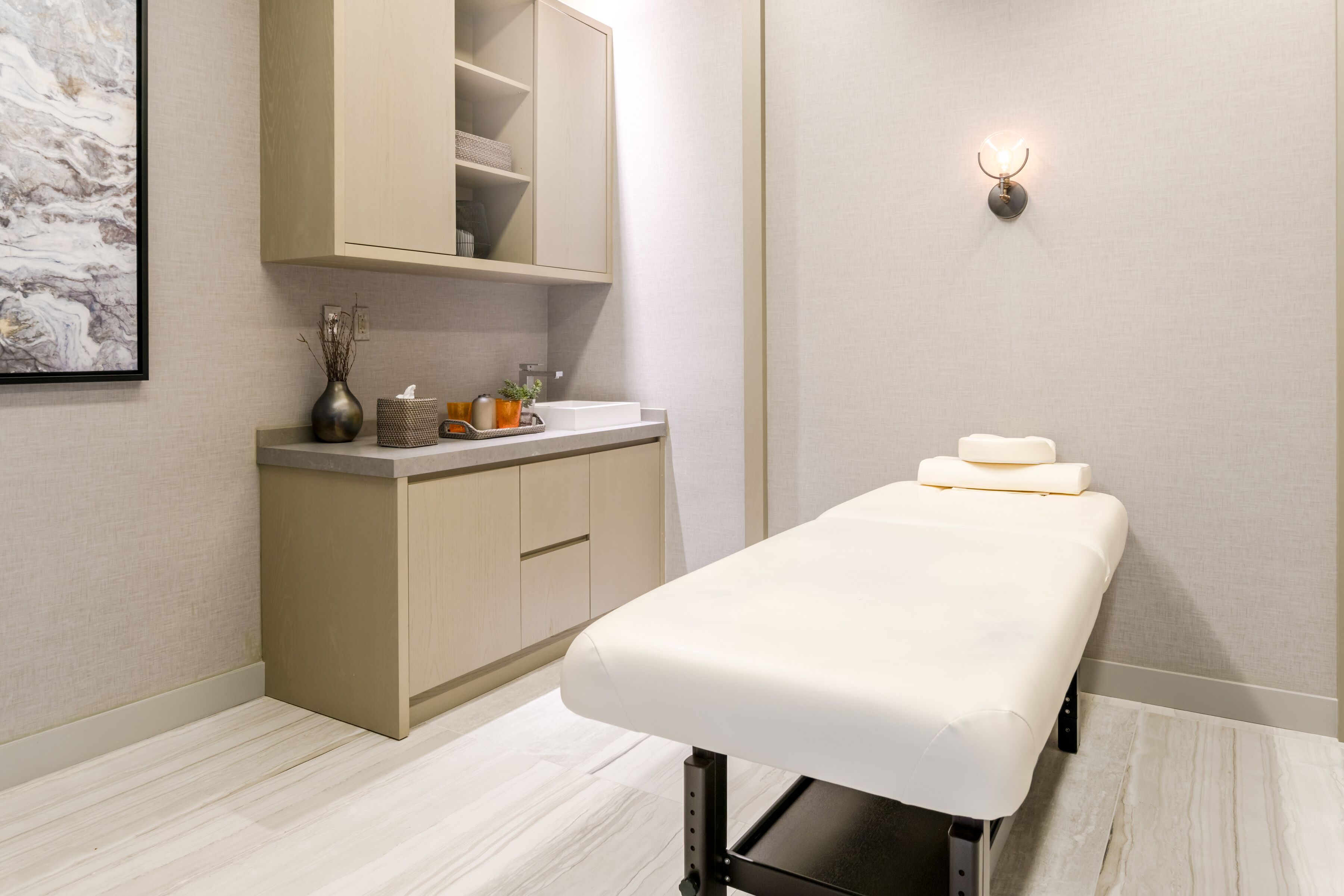 A clean, modern room with a wooden cabinet, a white bench with towels, and a wall-mounted light fixture.