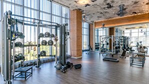 Une salle de sport spacieuse, dotée de divers appareils d’exercice, de grandes fenêtres et d’un plancher en bois.
