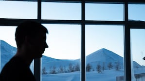 A person sitting at a desk with a laptop in front of a window with a view of a snowy landscape and mountains. - Sóti Lodge (Skagafjörour)