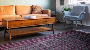 A living room with a sofa, a coffee table, a chair, a rug, and a window. - Sóti Lodge (Skagafjörour)