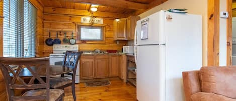 Una cocina acogedora con paredes de madera y un refrigerador blanco.
